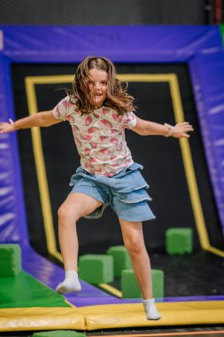 Havanın ortasında, neşeli bir yıldızın içinde, kapalı bir oyun merkezinde trambolinde, karpuz desenli tişört ve kot şortla atlayan genç bir kız..