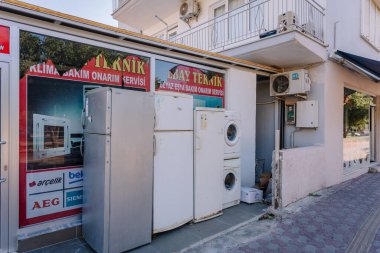 Kemer, Turkey - September 19, 2025 - Used home appliances, including refrigerators and washing machines, are displayed outside a small repair shop in a residential area in Turkey.