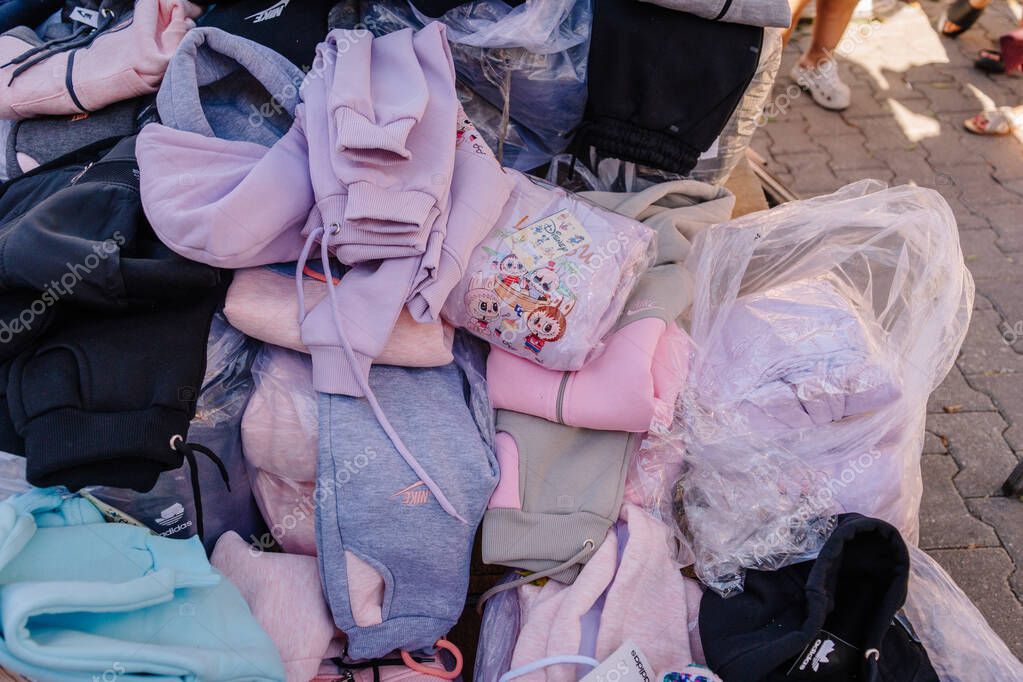 Kemer, Turkey - September 19, 2025 - A pile of assorted sweatshirts and tracksuits in pastel and neutral colors, many featuring visible brand logos like Nike and Adidas, displayed at a street market.