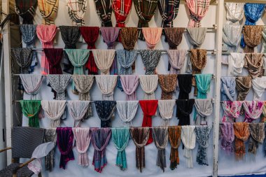 Kemer, Turkey - September 19, 2025 - Colorful scarves neatly displayed on rods in a market or boutique, showcasing a variety of patterns, textures, and vibrant hues for sale.