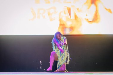 Kemer, Turkey - September 21, 2025 - A Raza Urbana dancer performs solo in colorful fringe costume under dramatic lighting, striking a powerful pose in front of a glowing screen on stage.