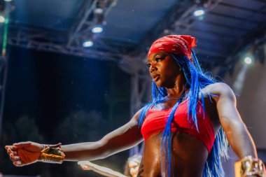 Kemer, Turkey - September 21, 2025 - Confident female dancer with blue hair and red bandana performs under stage lights during the Raza Urbana dance show. Intense focus and expression.