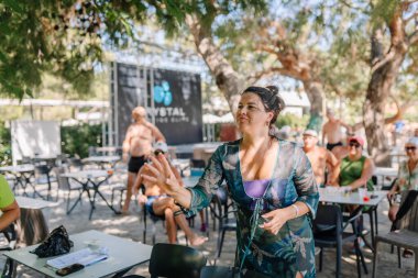 Kemer, Turkey, September 22, 2025 - A woman throws a dart during an outdoor game as spectators watch in a shaded area at a resort, creating a relaxed and fun holiday atmosphere.