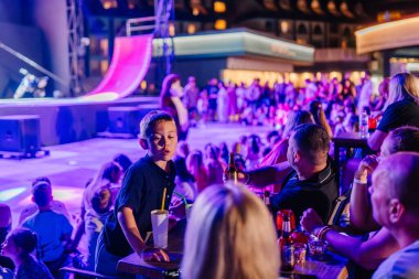 Kemer, Turkey, September 22, 2025 - Families and children gather with drinks and snacks to enjoy the Extreme Globe Show at night, creating a vibrant and lively atmosphere under colorful lights.