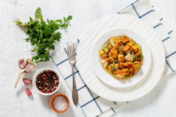 stock image turkey pot pie with stuffing crust served on white plate on white wood table with fork, horizontal view from above, flat lay