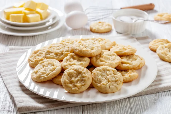 amish sugar cookies, traditional shortbread sweet cookies on white plate on white wood table with ingredients on background, american cuisine, horizontal view from above