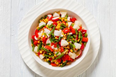 Charred Corn, Radish, Jicama, Red pepper and Green Bean Vegan Salad with Lime Olive oil Dressing in white bowl on white wood table, horizontal view from above, flat lay, close-up clipart