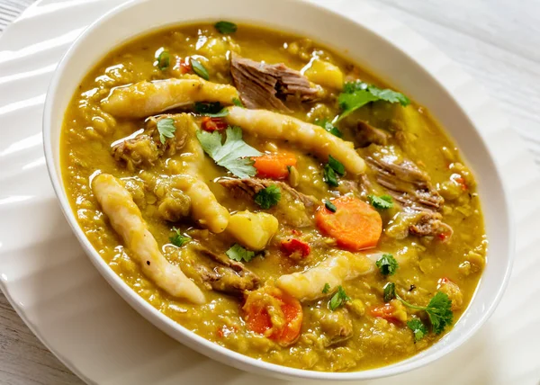 gungo peas, pigeon peas soup with dumplings , vegetables and beef in white bowl