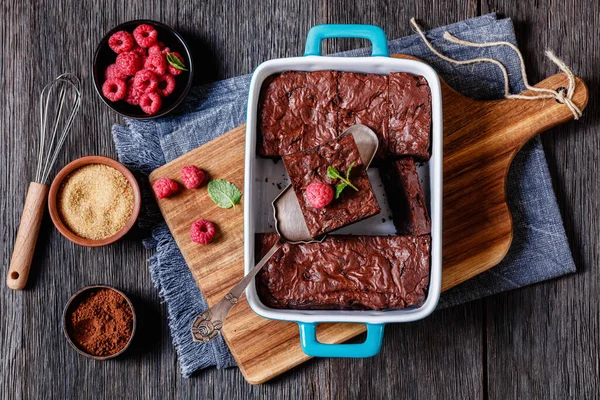 chocolate brownie with fresh raspberry and mint in a blue baking dish, horizontal view from above, flat lay