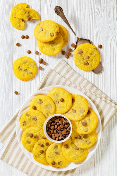 chocolate chip lemon yellow cookies on white plate on white wood table, american cuisine, horizontal view from above, vertical view