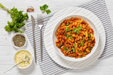Ground Chicken Pasta Bake with onion, mushrooms, spinach, tomato sauce and mozzarella cheese in white bowl on white wood table, horizontal view from above, flat lay clipart