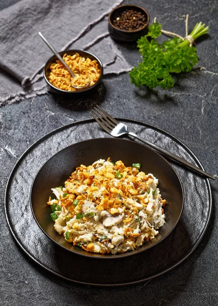 stock image Chicken Rice Mushroom Casserole D Iberville topped with french fried onion and crumbled crackers in black bowl on concrete table, vertical view