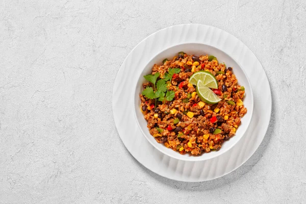 stock image Mexican Casserole of ground beef, rice, black beans, corn, green pepper and chopped tomatoes in white bowl on wood table, horizontal view from above, flat lay, free space