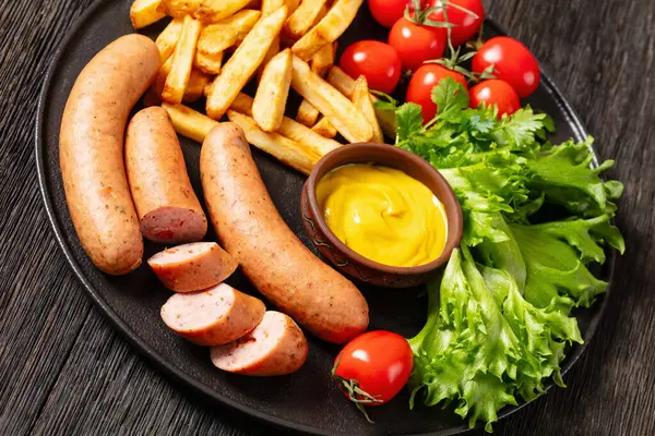 Italian Sausages French Fries Lettuce Fresh Tomatoes Mustard Black Plate — Stock Photo, Image