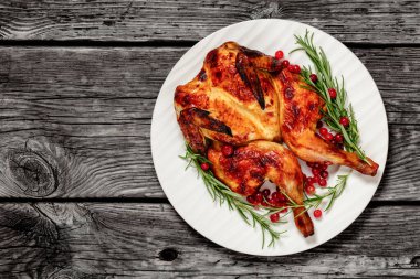 spatchcock roast whole chicken on plate with rosemary and cranberry, on grey wooden rustic table, horizontal view from above, flat lay, free space clipart