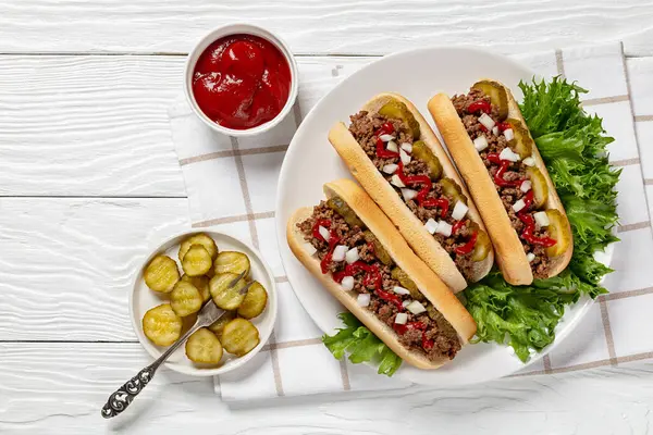 stock image Midwestern Loose Meat Sandwiches, Juicy burgers of ground beef topped with pickles, raw onion and ketchup on plate on white wooden table, horizontal view from above, flat lay, free space