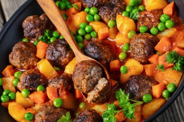 turkish meatball stew, sulu kofte, hearty dish with potatoes, carrot and green peas simmered in tomato sauce on a pan, close-up, dutch angle view clipart