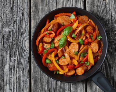 italian sausage peppers and onions simmered in zesty tomato sauce sprinkled with fresh basil and parsley on skillet on grey rustic table, horizontal view from above, flat lay, close-up clipart