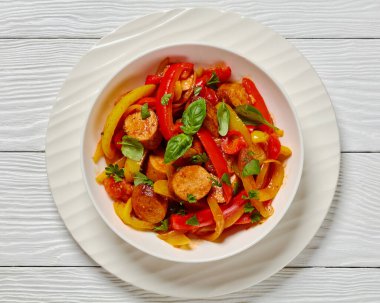 italian sausage peppers and onions simmered in zesty tomato sauce sprinkled with fresh basil and parsley in white bowl on white wooden table, horizontal view from above, flat lay, close-up clipart