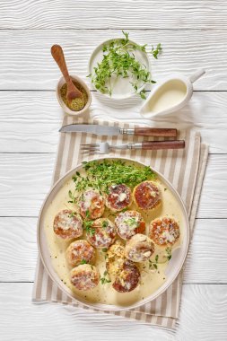 delicious chicken rissoles, patties in rich cream sauce with thyme and seasoning on plate on white wooden table with cutlery, vertical view from above, flat lay clipart