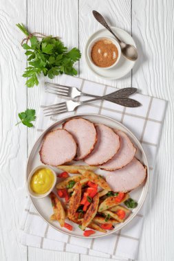 Schupfnudeln, fingernudeln, German potato thick noodles, dumplings with mustard and sous vide pork loin cut on a plate on white wooden table with forks and parsley, vertical view from above clipart