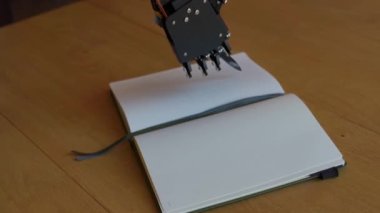 Robot bir el tarafından yazmak için kullanılacak boş bir defter.