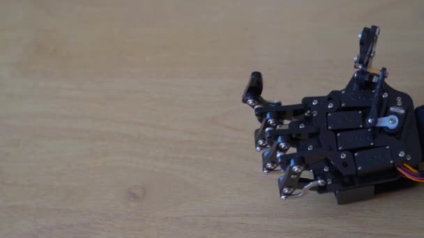 カメラがパンニングムーブメントを作る間 木のテーブルにロボットハンド — ストック動画