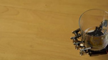 Kamera yavaş ve pürüzsüz bir dönüş yaparken Robotik El boş bir bardağı elinde tutar.