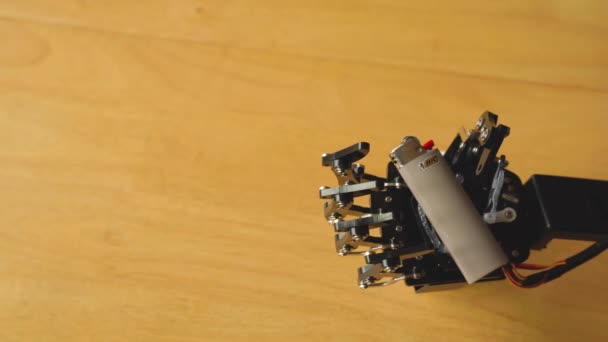 ロボットハンドは小さな灰色のライターを手に持っています — ストック動画