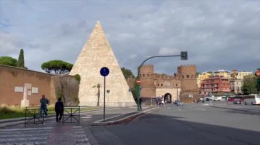 Cestius Piramidi 'nin arka planda şatosu olan videosu, sokaktan görüntülendi.