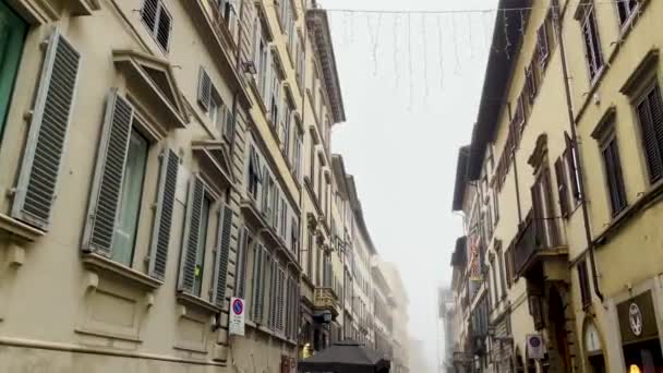 街道狭窄 建筑物之间挂着圣诞装饰品 背景上浓雾弥漫 — 图库视频影像