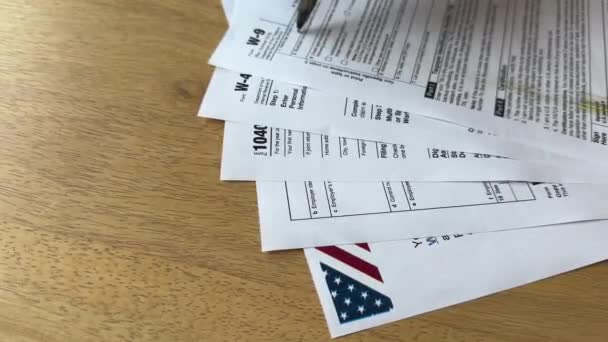 ロボットアームは 木製のテーブル上の米国の税務文書の配列の上に浮かび上がり 金融の自動化を示唆しています — ストック動画