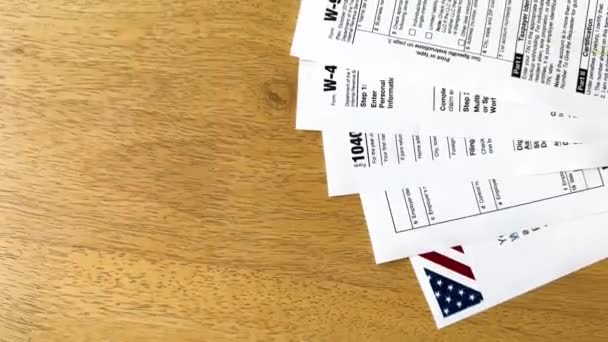 美国的各种税单 包括W 9和W 散落在一个木制的表面上 瞥见了美国国旗 — 图库视频影像