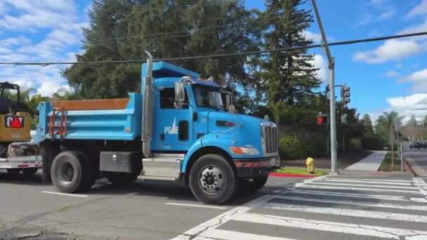 유틸리티 트럭은 배경에 무성한 녹지로 작업을 준비된 노란색 굴삭기를 운반합니다 — 비디오