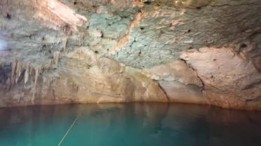 Saklı bir yeraltı mezarlığının sakin, kristal berrak suları karmaşık sarkıtlar ve engebeli kaya oluşumlarından oluşan bir tavanın altında parlıyor.