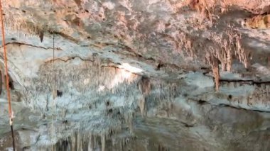 Karmaşık sarkıt oluşumları mağara çukurunun tavanını süsler ve binlerce yıl boyunca doğal sanatsal ve jeolojik evrimi sergiler.