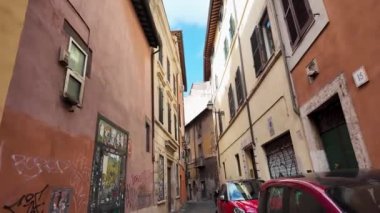Roma 'da dar bir sokak, park edilmiş arabalar ve duvarlarda grafiti var. Sahne, tarihi kentteki günlük yaşamın özünü yakalıyor..
