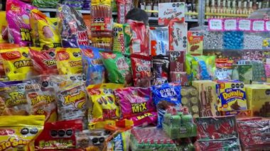 Bir dükkanda çok çeşitli renkli Meksika atıştırmalıkları sergileniyor. Çeşit çeşit şekerler, cipsler ve Meksika atıştırmalıklarının çeşitliliğinin sergilendiği paketlenmiş yiyecekleri içeriyor..