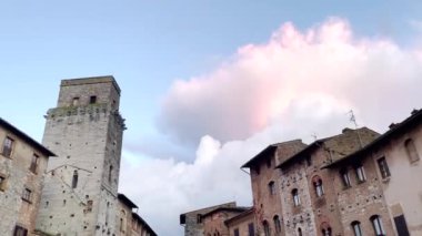  San Gimignano, Toskana, İtalya 'daki büyüleyici bir ortaçağ meydanında tarihi taş binalar ve huzurlu bir atmosfer sergileniyor. Görüntü, bu güzel kasabanın mimari güzelliğini ve kültürel mirasını vurguluyor..