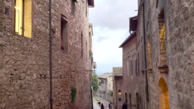 San Gimignano, Toskana, İtalya 'da dar kaldırım taşı yolları ve tarihi taş binaları olan tuhaf bir ortaçağ caddesi. Görüntü, bu güzel kasabanın görkemli cazibesini ve kültürel mirasını yansıtıyor..