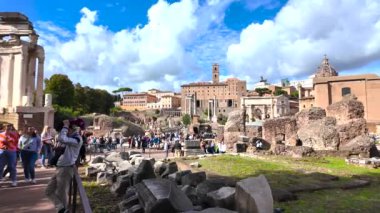 Roma 'daki antik kalıntılar ve bu tarihi bölgenin canlı atmosferiyle çevrili Roma Forumunu gezen turistler görülüyor. Güneşli bir gün, arkeolojik işaretlerin güzelliğini arttırır..