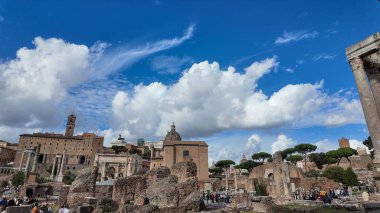 Roma 'daki Satürn Tapınağı, Roma Forumu' nun kalıntılarıyla çevrili. Sahne, tapınaklar arasındaki zıtlığı vurguluyor. Parlak gökyüzünün altındaki antik yapılarla korunmuş sütunlar arasında..