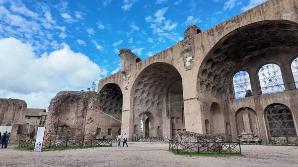 Maxentius Bazilikası 'nın büyük kemerleri Roma' da parçalı bulutlu bir gökyüzüne karşı dimdik ayakta duruyor. Bu etkileyici yıkıntı, antik Roma mühendisliğinin ölçek ve mimari hünerini yansıtıyor..