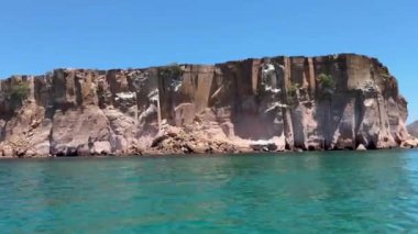 Sakin mavi okyanusun üzerinde dik bir kayalık, dramatik ve resimsel bir kıyı manzarası oluşturur. Kaya oluşumlarının ve berrak suların doğal güzelliği büyüleyici..