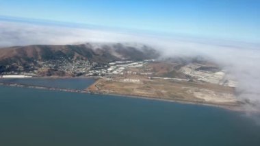 Çarpıcı bir hava manzarası, kıyı kasabasının üzerinde dağların ve okyanusun olduğu sisi yakalar. Sis, aşağıdaki doğal manzarayla pürüzsüz bir şekilde karışıyor..