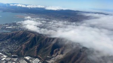 Sis kaplı dağların hava manzarası. Bulutlar alçaktan sarkıyor. Sahne, doğanın dingin güzelliğini yukarıdan yakalıyor..