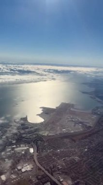 Okyanustan yansıyan güneşin ve suya doğru uzanan bir havaalanı pistinin olduğu çarpıcı bir kıyı kenti manzarası. Sabah ışığı, aşağıdaki manzara üzerinde huzurlu ve parlak bir ufuk yaratır..