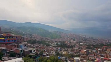 Yukarıdan Medelln 'in manzarası yeşil tepeleri aşan kalabalık mahalleleri gösteriyor. Şehir yoğunluğu ve doğal manzaranın eşsiz bir karışımı yakalanır. Başlık: Bir Tepeden Medelln 'in Manzarası