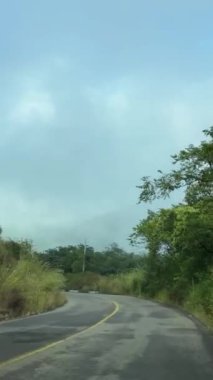 Parlak mavi gökyüzü ile dolambaçlı kırsal bir yol sisli tepelerin üzerinde, yemyeşil, harmanlanmış hava ve doğal güzelliklerle çevrili..