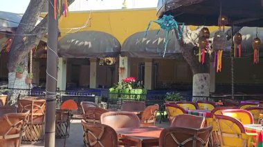 Chapala 'da renkli asma süsleri ve şemsiyelerle süslenmiş kırsal ahşap sandalye ve masalarla dolu canlı bir açık hava restoranı yemek için şenlikli bir atmosfer sunuyor..